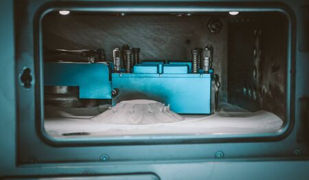 Object printed on metal 3d printer, laser sintering machine for metal close-up. A metal object sprinkled with metal powder after raising the platform into working chamber. DMLS, SLM, SLS technology.の写真素材