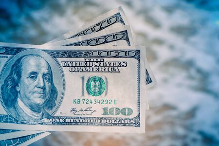 Girl holding money bill of 300 dollars on background of sea ocean waves with white foam and sand wet beach close-up. Hand wave sea ocean money dollars vacation. Concept finance money holiday travelingの写真素材