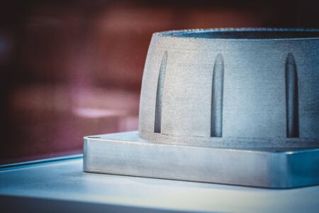 Man is holding object printed on metal 3d printer. Object printed in laser sintering machine. Modern...