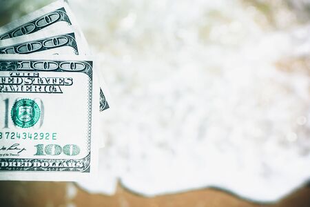 Girl holding money bill of 300 dollars on background of sea ocean waves with white foam and sand wet beach close-up. Hand wave sea ocean money dollars vacation. Concept finance money holiday travelingの写真素材