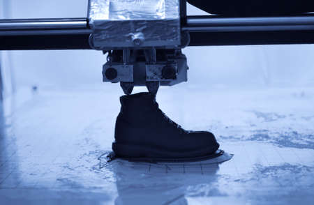 3D printer prints the form of molten plastic blue close-up.