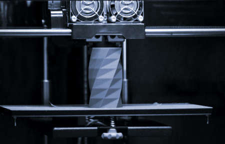 3D printer works and creates an object from the hot molten plasticの写真素材