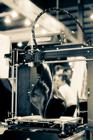 3D printer printing a model in the form of black vase close-up.