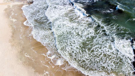 Aerial drone view flight over sea waves that roll onto sandy shore.の写真素材
