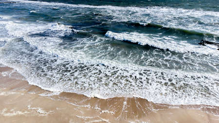 Aerial drone view flight over sea waves that roll onto sandy shore.の写真素材