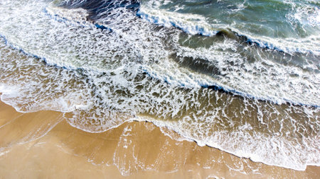 Aerial drone view flight over sea waves that roll onto sandy shore.の写真素材