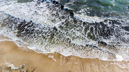 Aerial drone view flight over sea waves that roll onto sandy shore.の写真素材