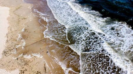 Aerial drone view flight over sea waves that roll onto sandy shore.の写真素材