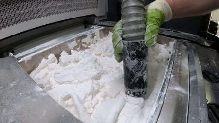 Man cleans details printed on industrial 3D printer from white plastic powderの写真素材