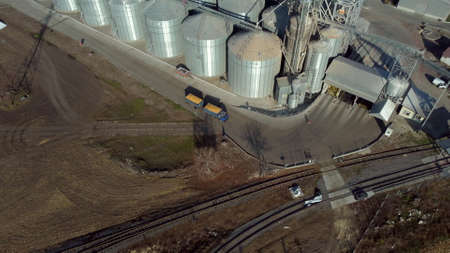 Truck filled with yellow grain drives near new metal modern elevator sunny dayの写真素材