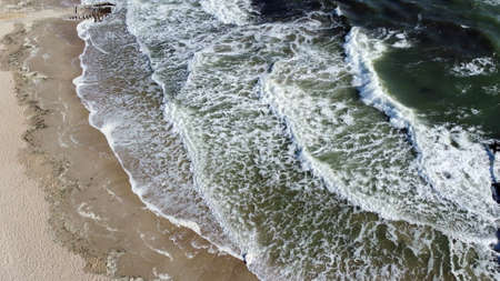 Aerial drone view flight over Beautiful sea waves on sand beach with white foamの写真素材