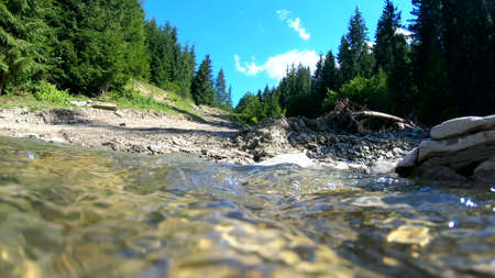 Beautiful mountain landscape scene with flowing river and bright reflectionの写真素材
