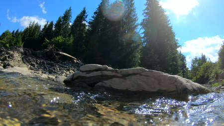 Beautiful mountain landscape scene with flowing river and bright reflectionの写真素材