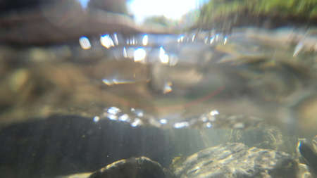 Flowing water, skylight of sun through water, stones lying at bottomの写真素材