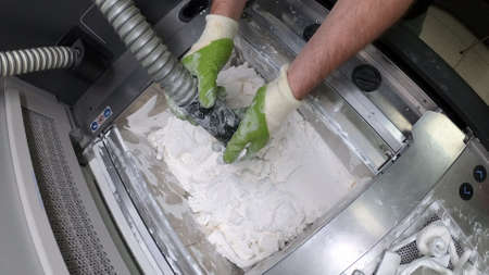 Man cleans details printed on industrial 3D printer from white plastic powderの写真素材
