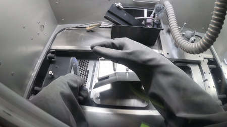 Male worker in rubber glove cleans printing platform inside 3d printer for metalの写真素材