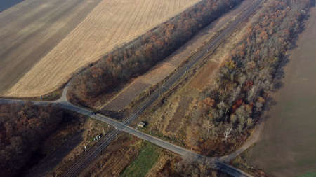 Panoramic View of Railroad Crossing Between Trees Fields Autumn Day Aerial Droneの写真素材