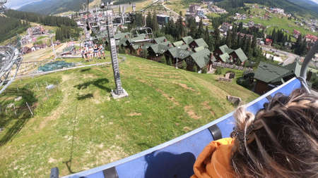 Girl rides or climbs on lift or cable car up mountain.の写真素材