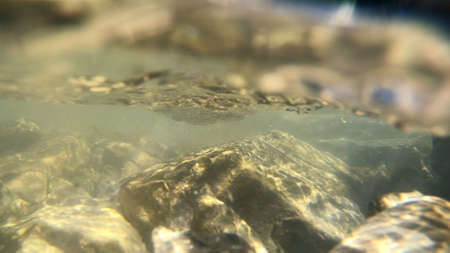 Flowing water, skylight of sun through water, stones lying at bottomの写真素材