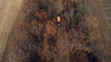 Aerial Drone View Flight Over Blue Tractor With Trailer Filled Yellow Corn Grainの写真素材