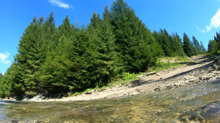 Beautiful mountain landscape scene with flowing river and bright reflectionの写真素材