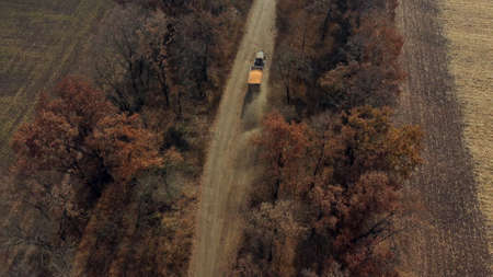 Aerial Drone View Flight Over Blue Tractor With Trailer Filled Yellow Corn Grainの写真素材