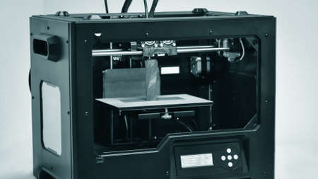3D printer works and creates an object from the hot molten plasticの写真素材