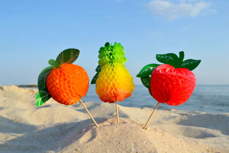 Bright Figure Colored Paper Decorations for Cocktail on Sandy Sea Beachの写真素材