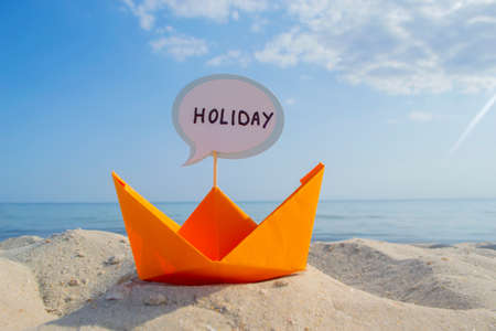 Orange Paper Boat on Sandy Seashore Close-up Small Boat from Paper on Backgroundの写真素材