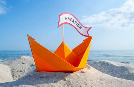 Orange Paper Boat on Sandy Seashore Close-up Small Boat from Paper on Backgroundの写真素材