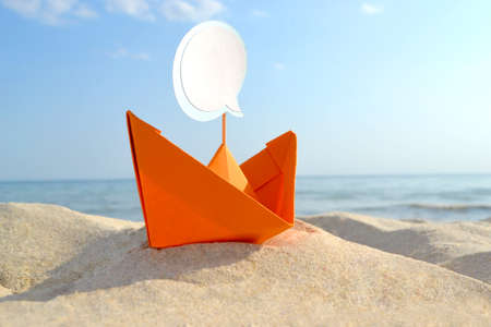 Orange Paper Boat on Sandy Seashore Close-up Small Boat from Paper on Backgroundの写真素材