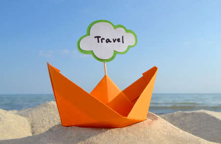 Orange Paper Boat on Sandy Seashore Close-up Small Boat from Paper on Backgroundの写真素材