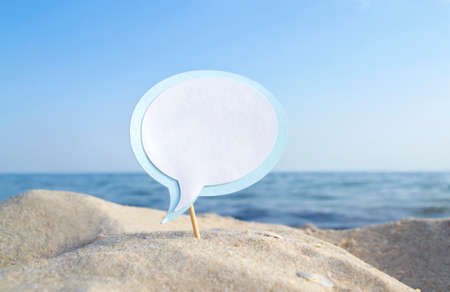 Empty blue white blank speech bubble on wooden stick on sandy sea beach close-upの写真素材