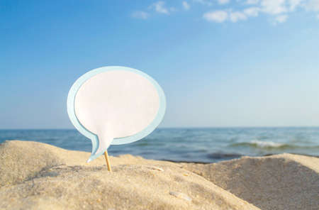 Empty blue white blank speech bubble on wooden stick on sandy sea beach close-upの写真素材