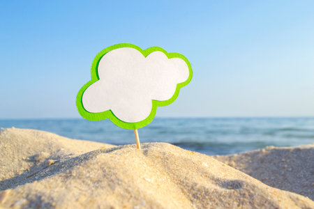 Empty blue white blank speech bubble on wooden stick on sandy sea beach close-upの写真素材