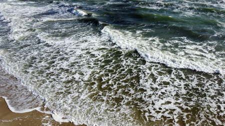 Aerial drone view flight over sea waves that roll onto sandy shore.の写真素材