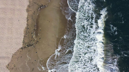 Aerial drone view flight over sea waves that roll onto sandy shore.の写真素材