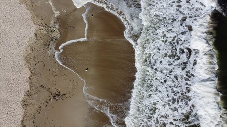 Aerial drone view flight over Beautiful sea waves on sand beach with white foamの写真素材