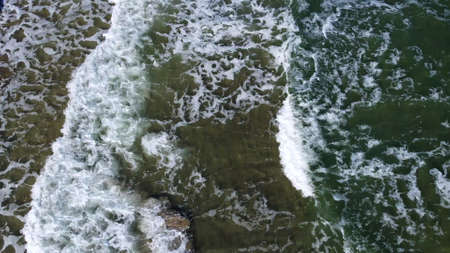 Aerial drone view flight over sea waves that roll onto sandy shore.の写真素材