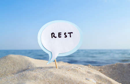 Empty blue white blank speech bubble on wooden stick on sandy sea beach close-upの写真素材