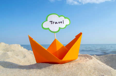 Orange Paper Boat on Sandy Seashore Close-up Small Boat from Paper on Backgroundの写真素材