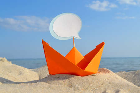 Orange Paper Boat on Sandy Seashore Close-up Small Boat from Paper on Backgroundの写真素材