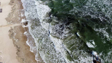 Aerial drone view flight over sea waves that roll onto sandy shore.の写真素材