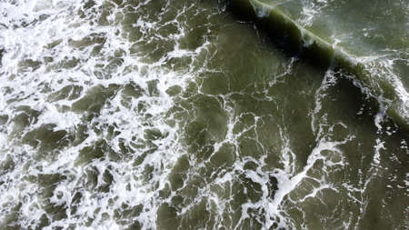 Aerial drone view flight over sea waves that roll onto sandy shore.の写真素材