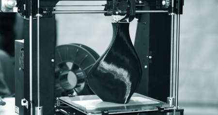 3D printer printing a model in the form of black vase close-upの写真素材