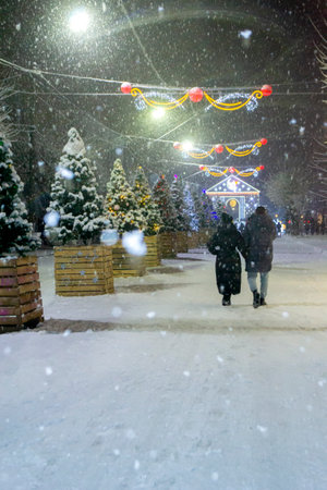 Snowy city street with Christmas trees and illumination decorationの写真素材