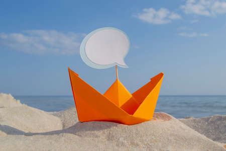 Orange Paper Boat on Sandy Seashore Close-up Small Boat from Paper on Backgroundの写真素材