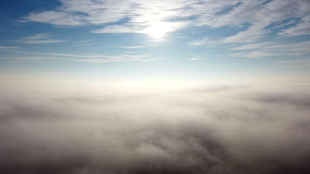 Aerial drone view flight over fog and under clouds with shining sun shining.の写真素材