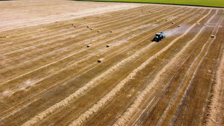 Hay bale tractor. Tractor harvesting hay into bales in field on sunny day Baling