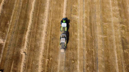 Hay bale tractor. Tractor harvesting hay into bales in field on sunny day.の素材 [FY310184771616]